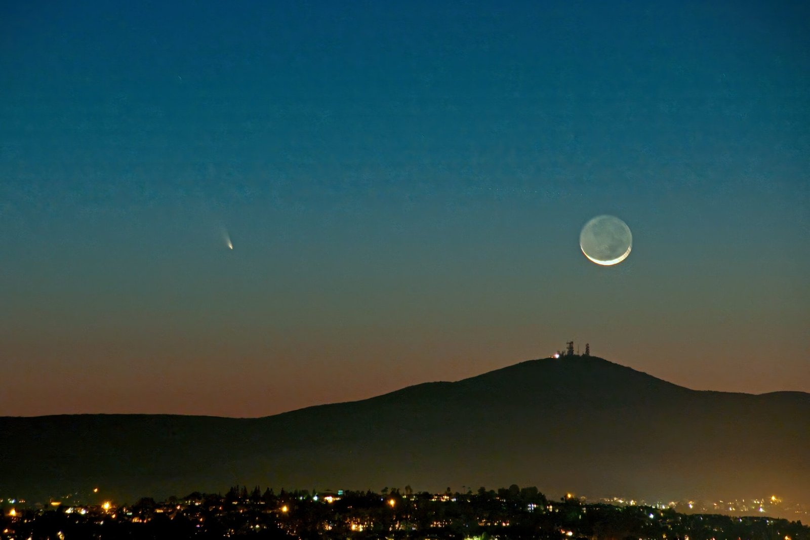 Comet PANSTARRS above the western horizon, with the silhouette of Black Mountain and city lights, photographed from Poway Road in Poway, San Diego County.